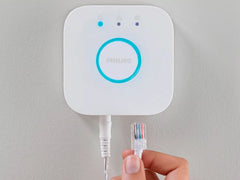 Philips Hue Bridge, älyvalaistuksen ohjauskeskus, kytkettynä internetiin, valkoinen muotoilu, kiinnitysseinälle.