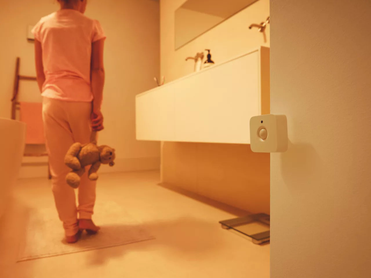 Philips Hue liiketunnistin näkyy kodin kylpyhuoneessa, kun lapsi kulkee pehmolelu mukanaan.